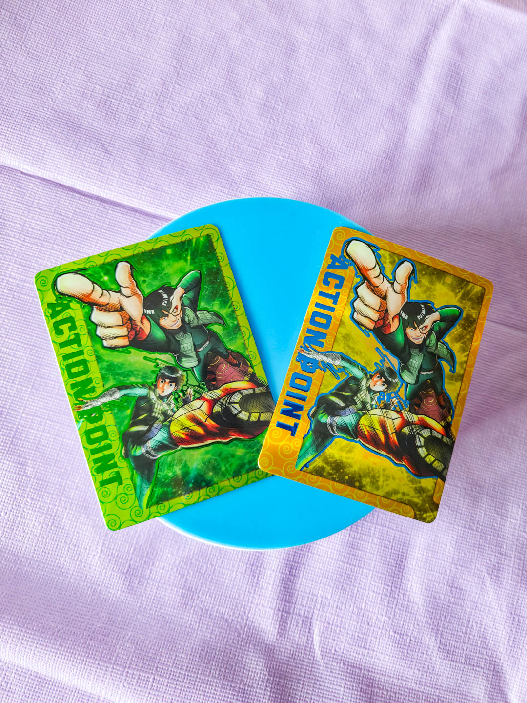 Two action figure trading cards on a light purple fabric background